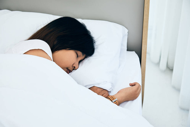 Κοντινό πλάνο Ασιάτισσα γυναίκα κοιμάται σε λευκό κρεβάτι στην κρεβατοκάμαρα με γλυκά όνειρα και απολαμβάνει καλή ξεκούραση στο σπίτι - Φωτογραφία, εικόνα