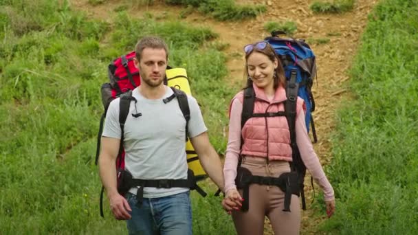 szczęśliwa para, mężczyzna i kobieta w górach, podróżują w poszukiwaniu miejsca na wakacje. radują się, stojąc na tle pięknego krajobrazu. wakacje w górach - Materiał filmowy, wideo
