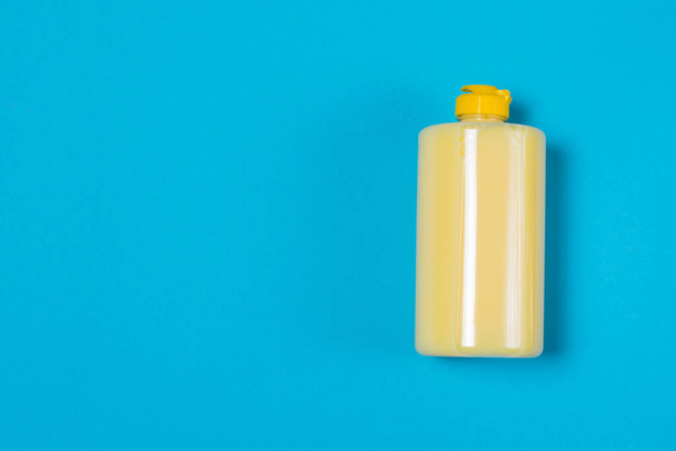 Detergente de lavagem de louça amarelo com aroma de banana em um fundo azul com espaço de cópia. - Foto, Imagem