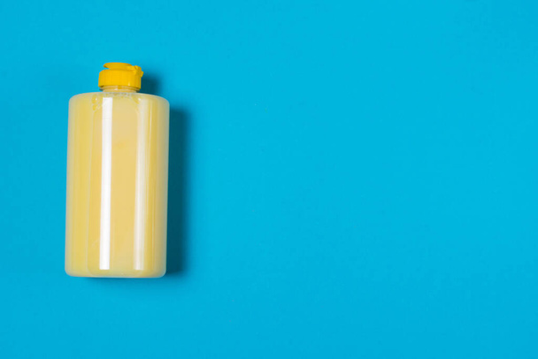 Жовтий миючий засіб для посуду з ароматом банана на синьому фоні з копіювальним простором
. - Фото, зображення