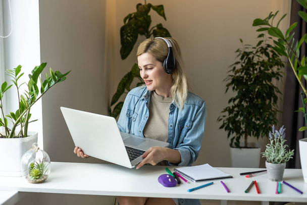 Bild von jungen erfreut glücklich fröhlich niedlich schöne Geschäftsfrau sitzen drinnen im Büro mit Laptop-Computer Musik hören mit Kopfhörern. - Foto, Bild