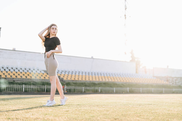 Full Body Slender Girl at the Stadium at Sunset on a Summer Evening. The girl is standing in front of the podium. Copy Space. - Valokuva, kuva