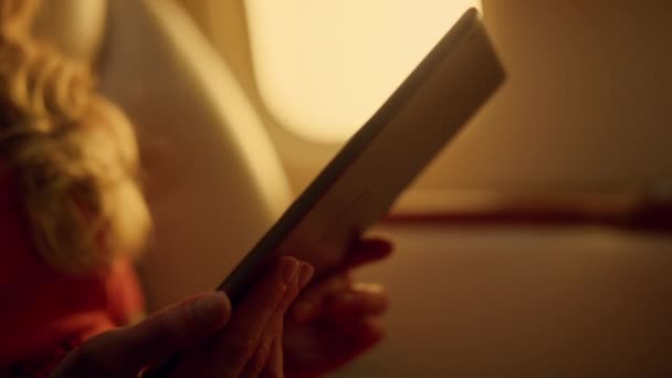 Femme regardant l'écran de la tablette verte sur le voyage en avion. Mains tenant le coussin en gros plan. Passager non reconnu utilisant un appareil de maquette voyageant en première classe. Travail réussi d'analyse des données sur les voyages d'affaires - Séquence, vidéo