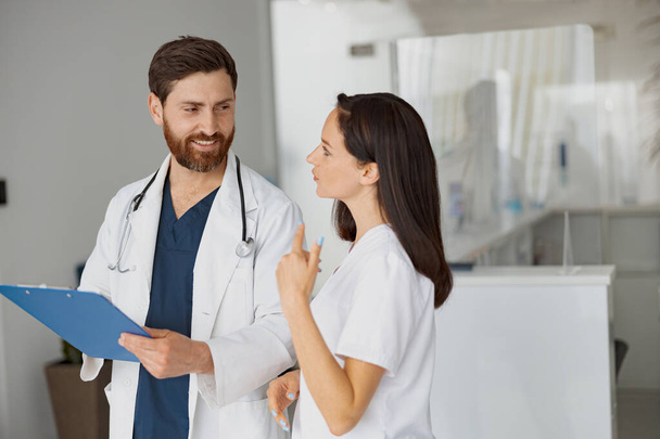 Doctor and nurse solve work issues standing near reception in clinic. High quality photo - Photo, Image