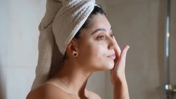 Close up beautiful half naked woman applying face cream and looking away isolated - Footage, Video