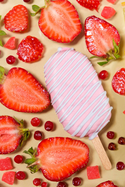ピンク色のアイスクリーム、イチゴと赤のリンゴンベリーがベージュの背景にあります。 - 写真・画像
