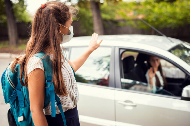 Mother in car, dropping off her daughter to the school and wishing her a good day. Back to school, motherhood concept. - Valokuva, kuva