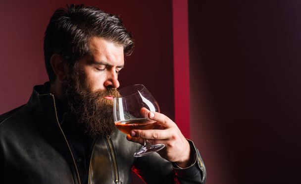 Acımasız adam viski tadıyor. Sert alkol. Deri ceketli sakallı adam konyak ya da konyak kokluyor. - Fotoğraf, Görsel