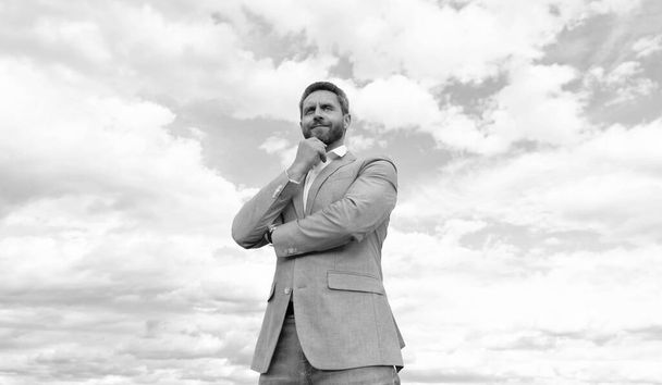 красивый зрелый мужчина бизнесмен в формальном костюме проверить время на наручные часы на фоне неба, формальная мода. - Фото, изображение