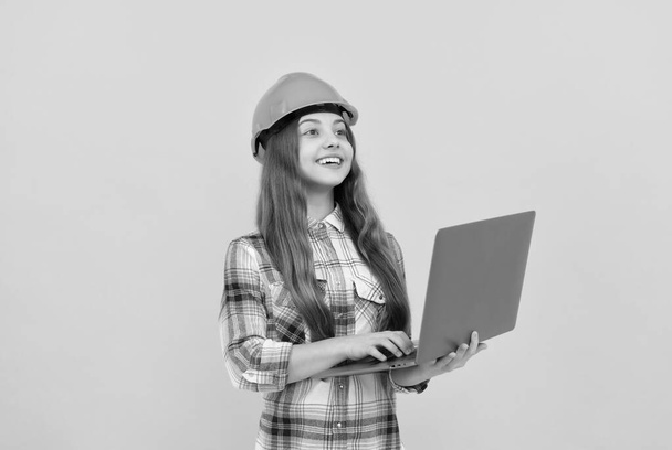 muchacha adolescente feliz en casco y camisa a cuadros usando el ordenador portátil, escuela. - Foto, imagen