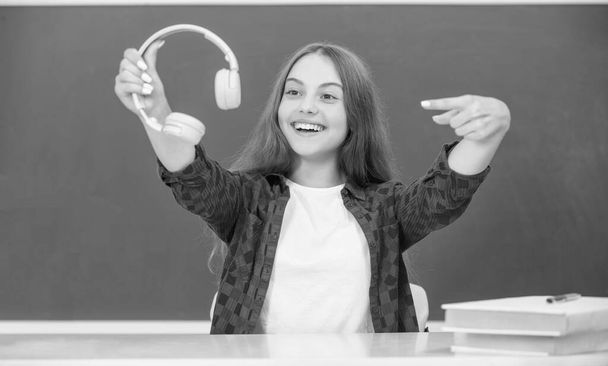 無線ヘッドセット装置付属品。新しい技術だ。幼児期の発達。現代のイヤホンの子供です。オンライン教育です。幸せな10代の女の子のポイント指のヘッドフォンです。音楽好き。音楽を聴け. - 写真・画像