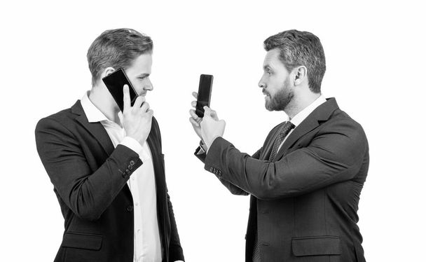 Verhandlungsuneinigkeit über sprechenden Mann auf Smartphone und Geschäftsmann zeigt Telefon isoliert auf weiß, argumentieren. - Foto, Bild