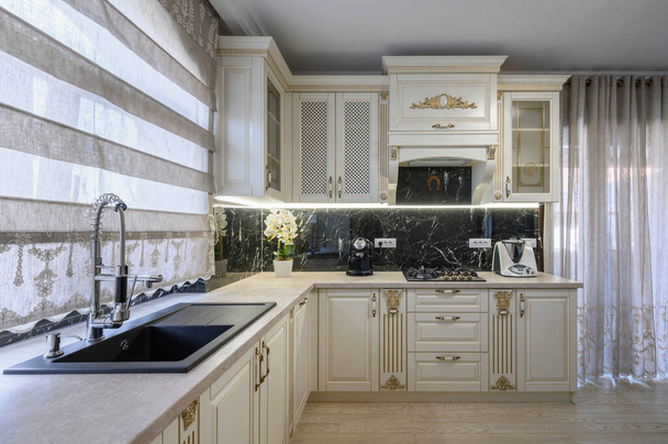 Современная классическая белая и бежевая кухня со столовой в интерьере однокомнатной квартиры - Фото, изображение