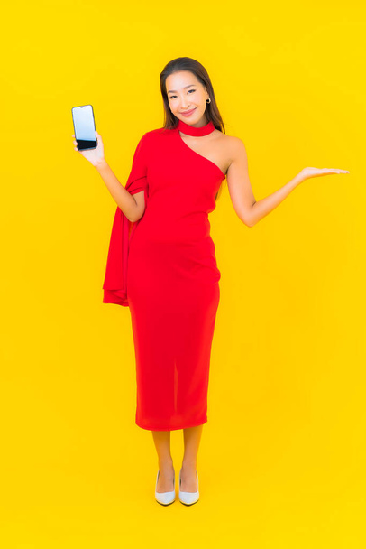 Портрет красива молода азіатка зі смартфоном з кредитною карткою на жовтому фоні
 - Фото, зображення