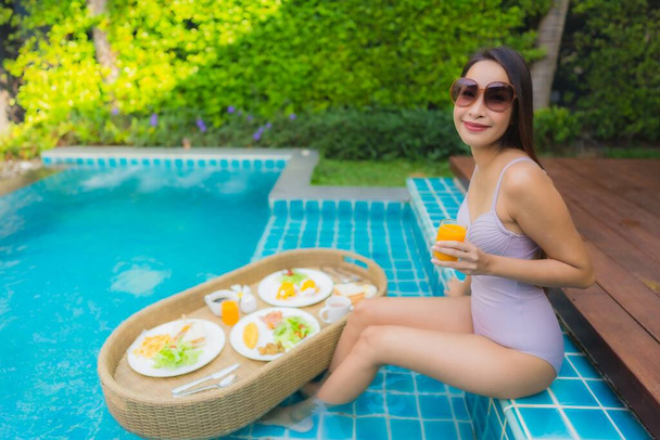 Портрет молодої азіатки щаслива усмішка насолоджується плаваючим сніданком у басейні в готельному комплексі
 - Фото, зображення