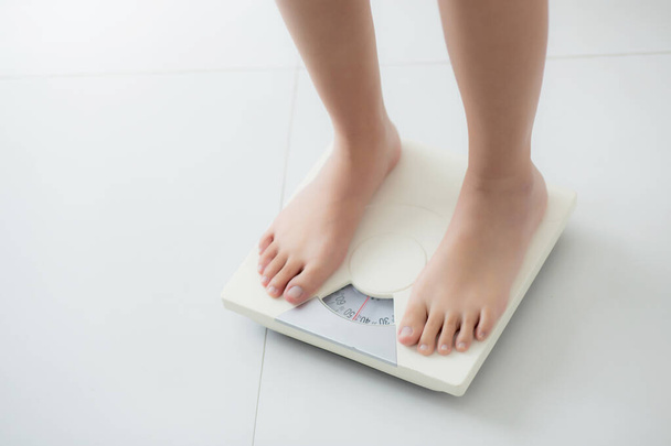 Stopa zbliżeniowa kobiety stojącej na wadze mierzącej wagę kontrolną w pomieszczeniu, nadwaga i dieta, zdrowie i utrata wagi, badanie tkanki tłuszczowej z ważeniem, wewnętrzne, zdrowe koncepcje. - Zdjęcie, obraz