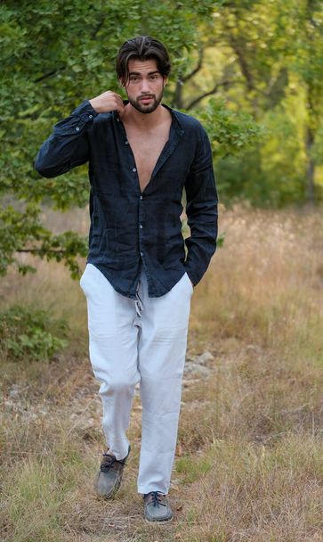 乾いた草の中にシャツを着たハンサムなイタリア人の黒髪の男。高品質の写真 - 写真・画像