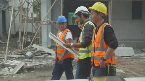 Groep team van ingenieur en architect met aannemer lopen en inspecteren over de regeling bouwplaats voor de planning van het project aan de werknemer en op zoek blauwdruk, bouwplaats, ontwikkeling en structuur. - Video