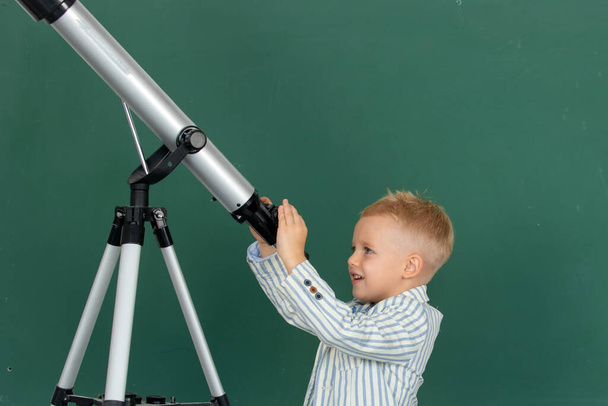 Cute school kid pupil study with telescope in a classroom - Photo, Image