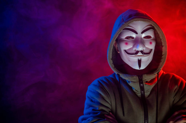 June 5, 2022 Novosibirsk, Russia: Hooded portrait of Anonymous in the dark in red-blue smoke - Photo, Image
