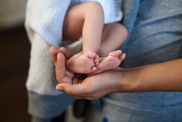 Mom keeps  miniature newborn leg in hand - Foto, Imagen