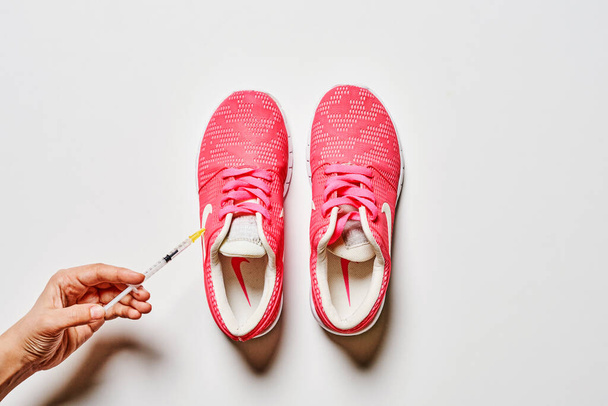 Zapatillas deportivas e inyección sobre fondo blanco. Equipamiento deportivo, consepto Doping. - Foto, Imagen