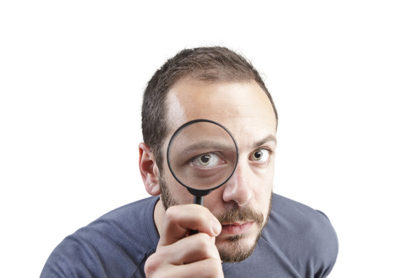 Astonished man looking through a magnifying glass - Zdjęcie, obraz