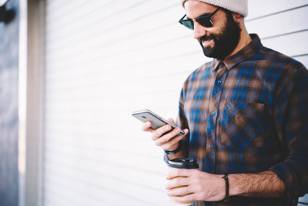 Middle Eastern hipster guy in sunglasses using mobile technology for making online booking and baking during travel vacations - Φωτογραφία, εικόνα