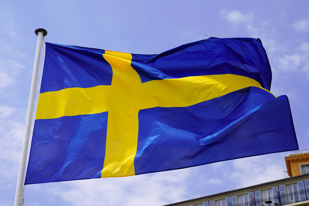 Flaga Szwecji przeciwko błękitnemu niebu w tkaninie niebieski żółty krzyż kolory - Zdjęcie, obraz