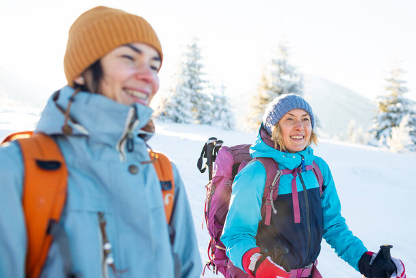 Kaksi naista reppuineen kävelee lumessa, talvivaellus, kaksi ihmistä vuorilla talvella, vaellusvälineet - Valokuva, kuva