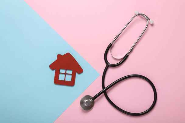 Stetoscopio con modello di casa su sfondo rosa blu. Concetto di assicurazione medica - Foto, immagini
