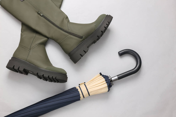 Rubber trendy boots with umbrella on a gray background. Top view - Foto, imagen
