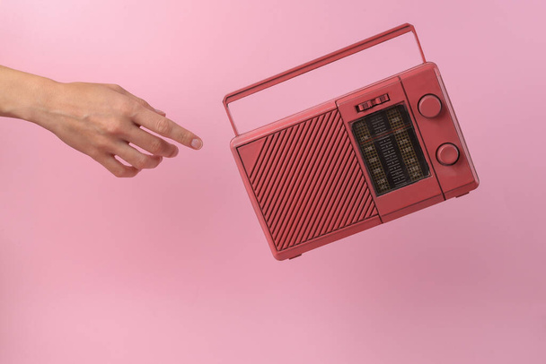 Alcanza la mano para levitar receptor de radio retro fm sobre fondo rosa - Foto, imagen