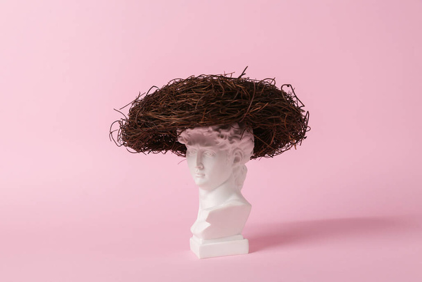 Antique bust of David with nest on a pink background. Conceptual pop. Minimal still life. Creative idea - Photo, Image