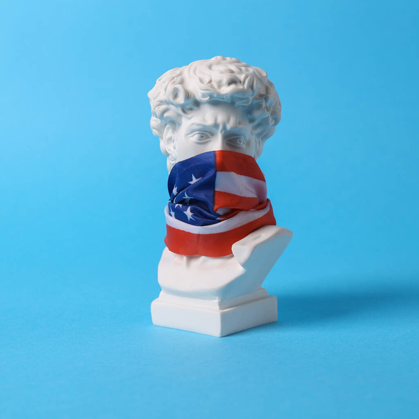 David bust with usa flag on his face against blue background. Patriotism. Minimal still life - Фото, изображение