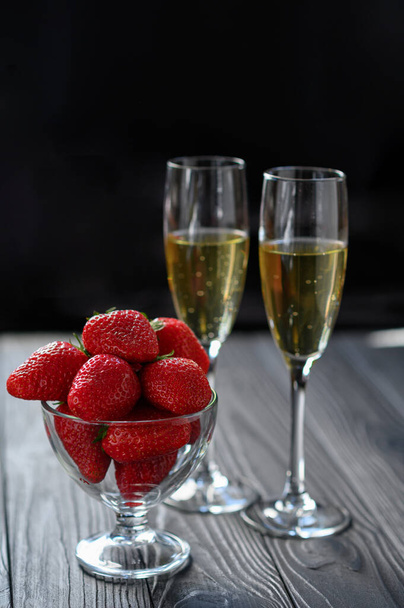 strawberries and champagne in a glass on a black background - Photo, Image