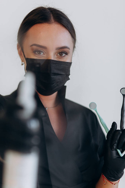 Dentista in cappotto nero e cavalletti porta occhiali con strumenti dentali - Foto, immagini
