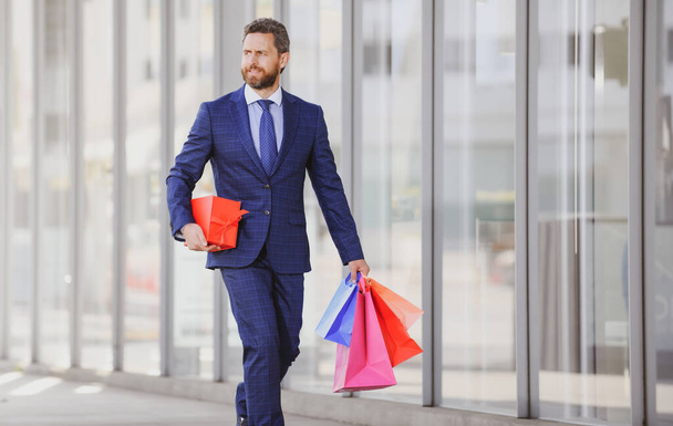 Business man holding shopping bags and walking in shopping store. Shopping and paying. Shopaholic shopping concept - Φωτογραφία, εικόνα