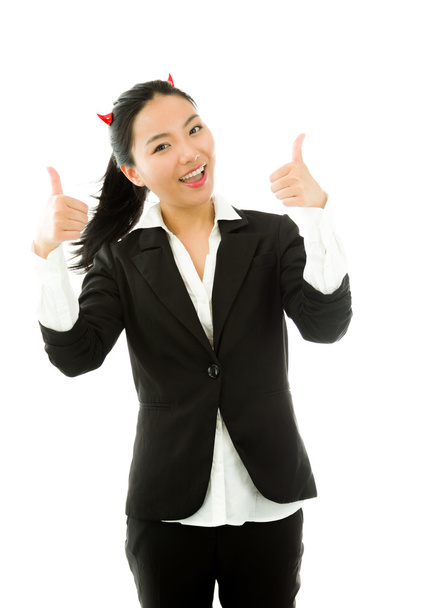 Lado diabólico de una joven empresaria asiática mostrando el pulgar hacia arriba con ambas manos y sonriendo aislada sobre fondo blanco
 - Foto, imagen