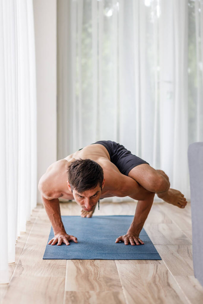 Young man doing strength pilates or yoga workout in the morning. Muscular man practicing sweat yoga at home - Foto, imagen