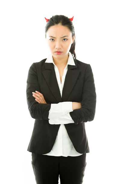 Lado diabólico de una joven empresaria asiática de pie con los brazos cruzados y mirando triste aislada sobre fondo blanco
 - Foto, Imagen