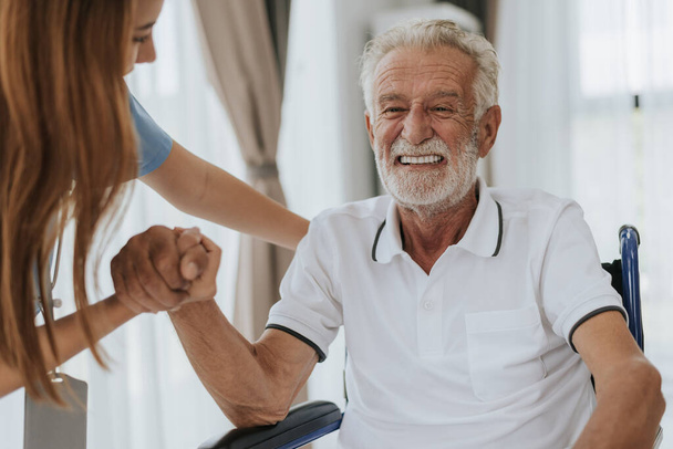 Nővérkéz, hogy segítsen és támogassa az idősebb embert. A fiatal ápolónő és az idősebb férfi kéz, hogy támogassák egymást. Segítségnyújtás, idősgondozás. - Fotó, kép