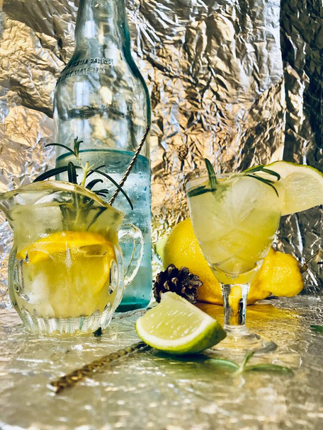 Bevanda fredda al limone in cui si può aggiungere un po 'di alcol con cubetti di ghiaccio e menta su fondo d'acciaio con candele - Foto, immagini