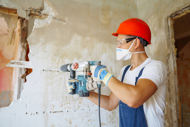 Repairer in hardhat  and boiler suit with tools. Apartment repair and renovation concept. Building, working equipment and people concept - Valokuva, kuva