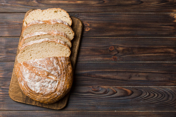 Frissen sült kenyérszeletek vágódeszkán fehér fa háttér mellett. top view szeletelt kenyér. - Fotó, kép