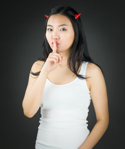 Asyalı genç kadın şeytan boynuzu parmağında sessizlik için soran dudaklarında - Fotoğraf, Görsel