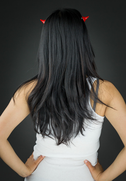 Visão traseira de uma jovem mulher asiática em chifres do diabo com seus braços akimbo
 - Foto, Imagem