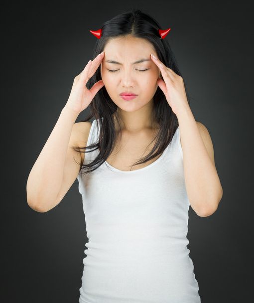 Mujer joven asiática estresada en cuernos de diablo que sufren de dolor de cabeza
 - Foto, imagen