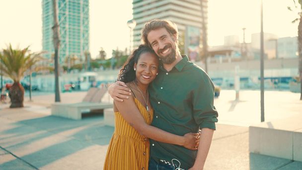 Close-up portrait of happy interracial couple in the port, backlighting Closeup, young woman and man hugging and smiling looking at the camera - Fotó, kép
