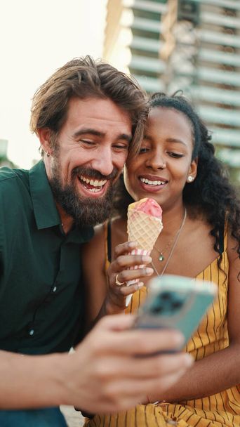 portrait of happy man and smiling woman watching video on smartphone. Close-up of joyful young interracial couple browsing photos on mobile phone on urban city background - Foto, imagen